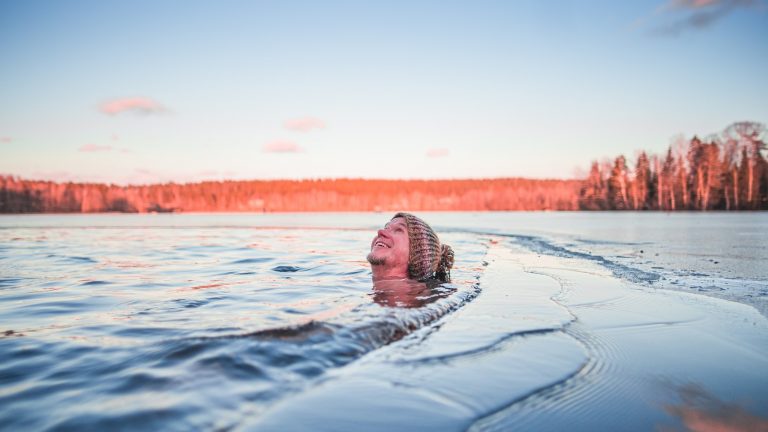 A man winter swimming with a woollen hat on