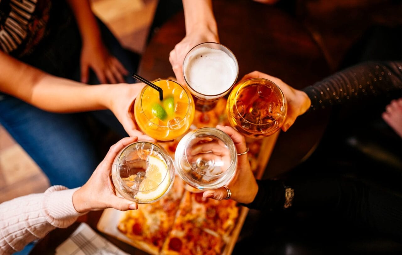 Ihmisporukka kippistää erilaisia drinkkejä, olutta sekä siideriä.