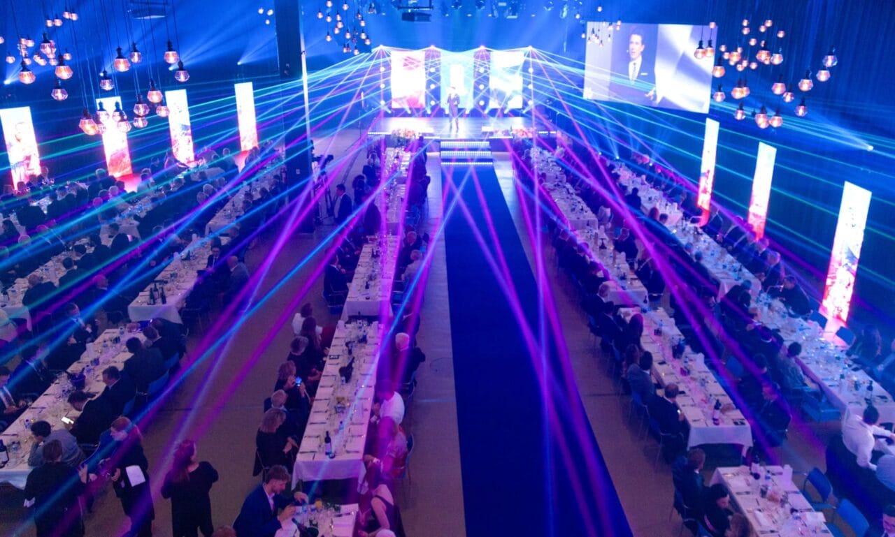 Long banquet tables and neon lights in a large event space | Pitkät juhlapöydät ja neonvalot suuressa juhlatilassa