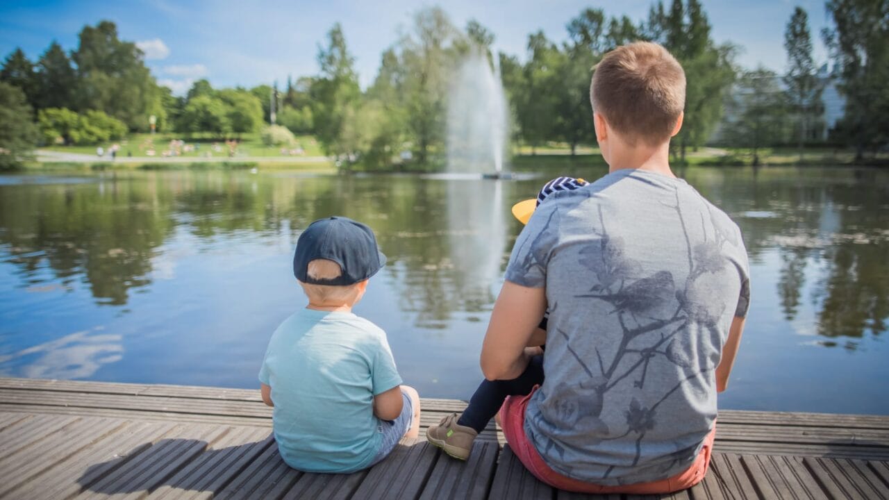 Family sitting on the pier in Sorsapuisto park.