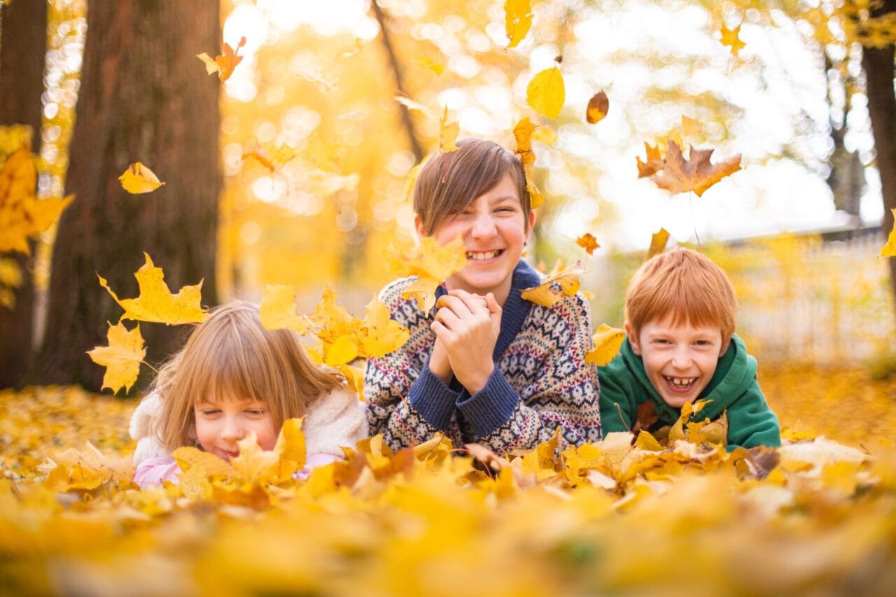 Three children playing with leaves.