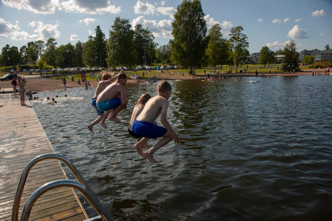 Pojat hyppäävät laiturilta.