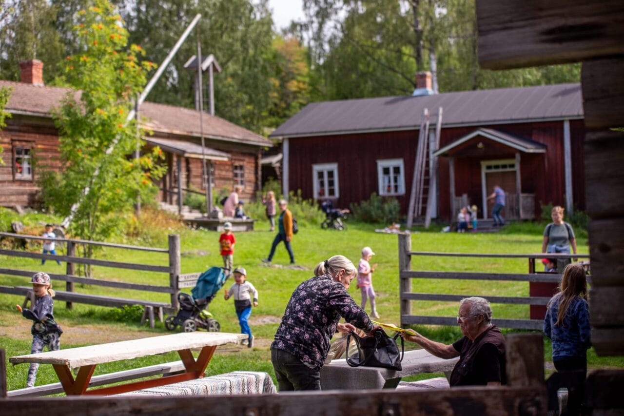 Lapsia juoksentelee Talonpoikaismuseo Yli-Kirran pihassa ja isovanhemmat katselevat menoa.