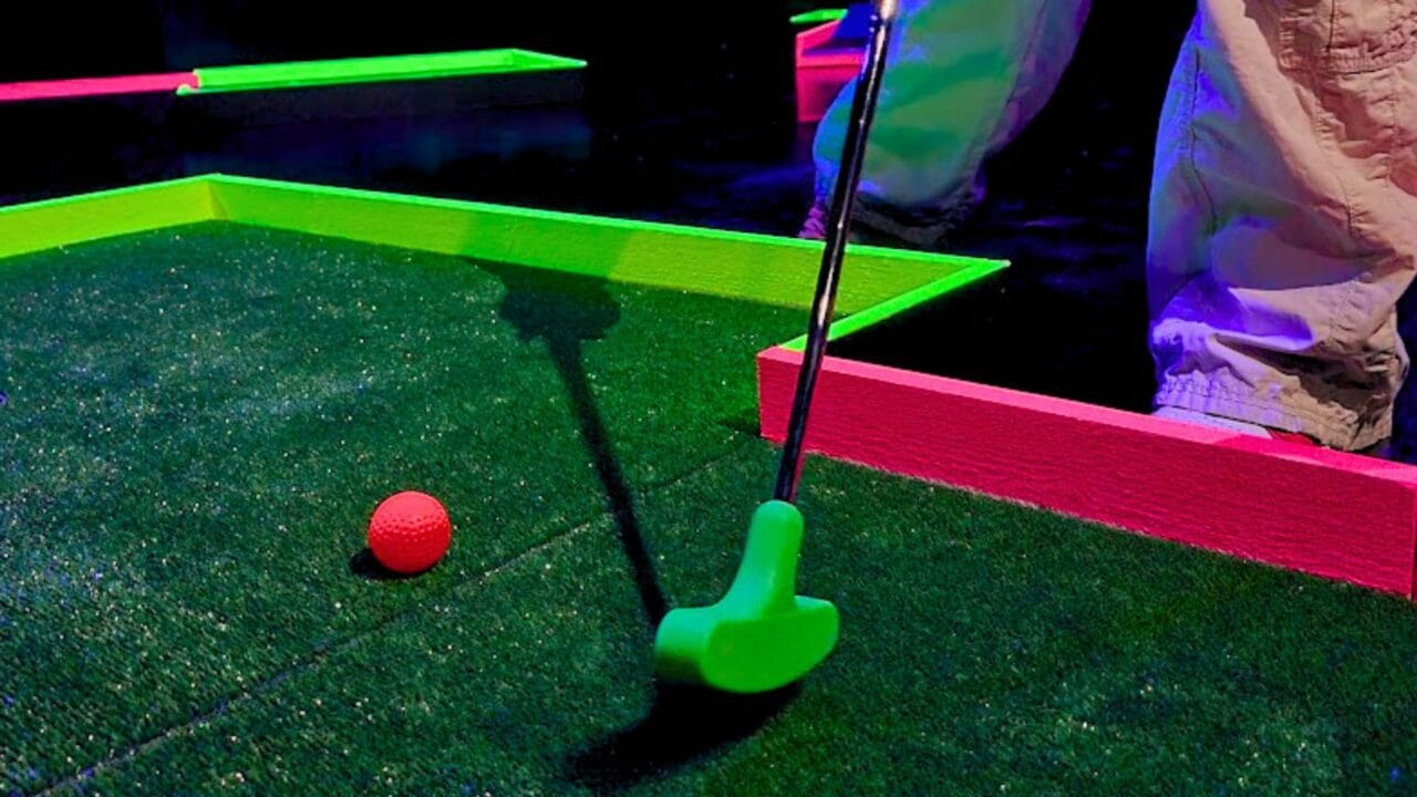 A close-up of a minigolf club hitting a ball in Hohtogolf Tullintori